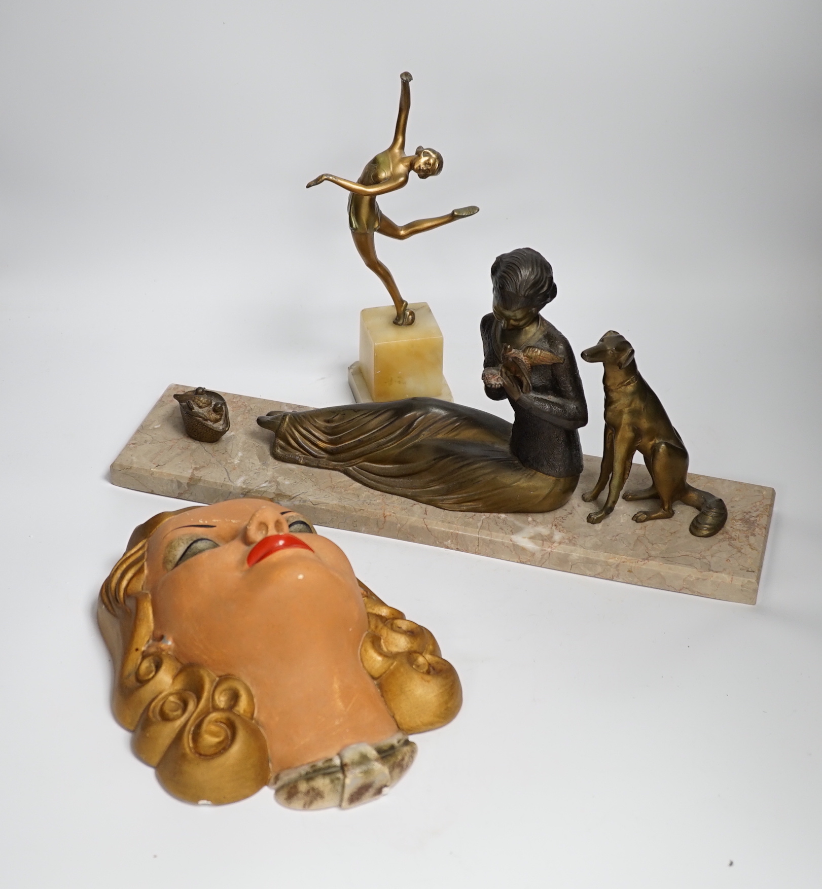 An Art Deco model of a seated lady with a dog and doves, together with a figure of dancing girl and painted plaster face mask, longest 45cm